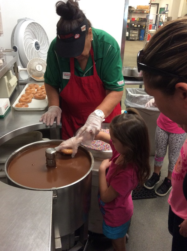 Children visit Krispy Kreme for a field trip helping workers make Chocolate Donuts.