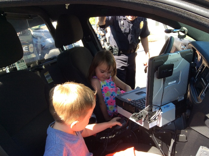 Two Children sitting in the front seats of a Police Car exploring for fun.