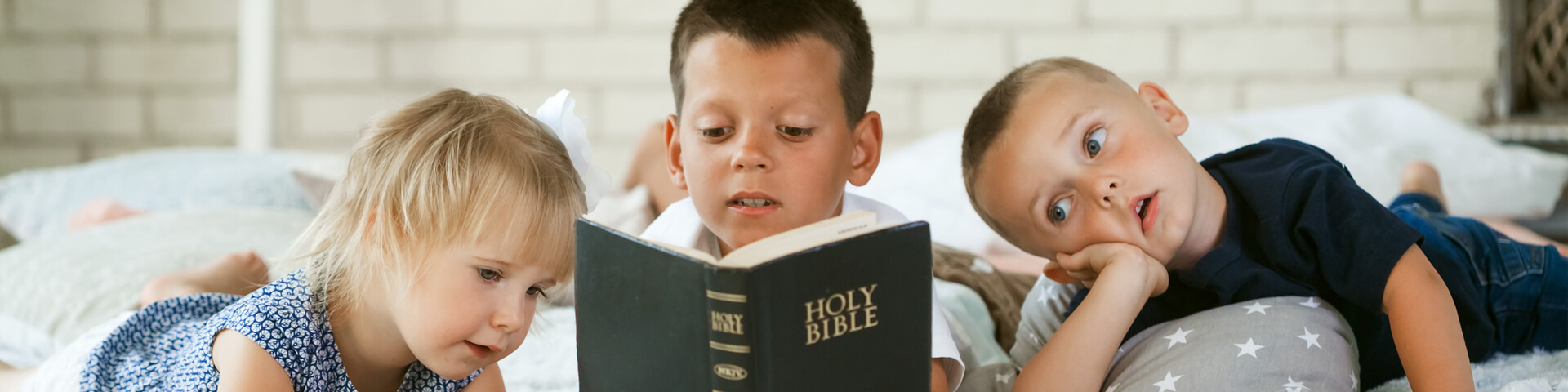 Three Kids, Child in the middle holding the bible so all Three can read it together.